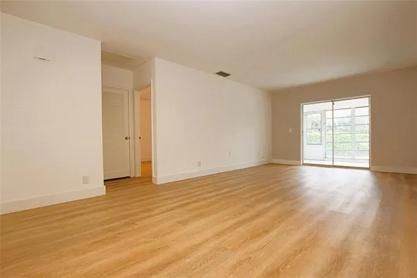 a view of an empty room with wooden floor and a window