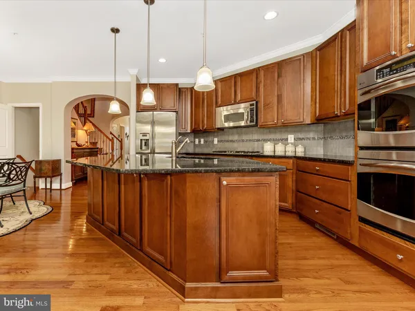 a kitchen with stainless steel appliances granite countertop wooden cabinets a sink a stove a dining table and chairs