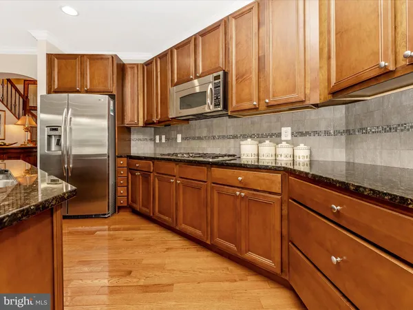 a kitchen with stainless steel appliances granite countertop wooden cabinets a stove top oven a sink and dishwasher