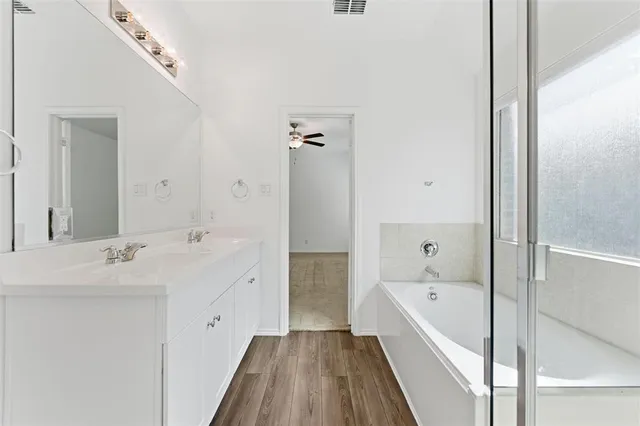 a spacious bathroom with a tub sink and mirror