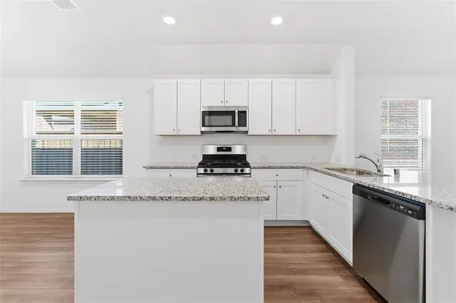 a kitchen with granite countertop white cabinets and black stainless steel appliances