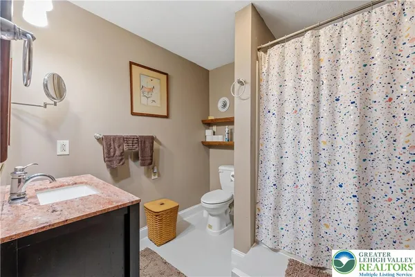 a bathroom with a granite countertop sink and a toilet