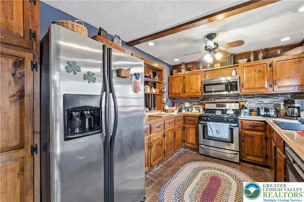 a kitchen with stainless steel appliances granite countertop a refrigerator a stove and a sink with wooden floor