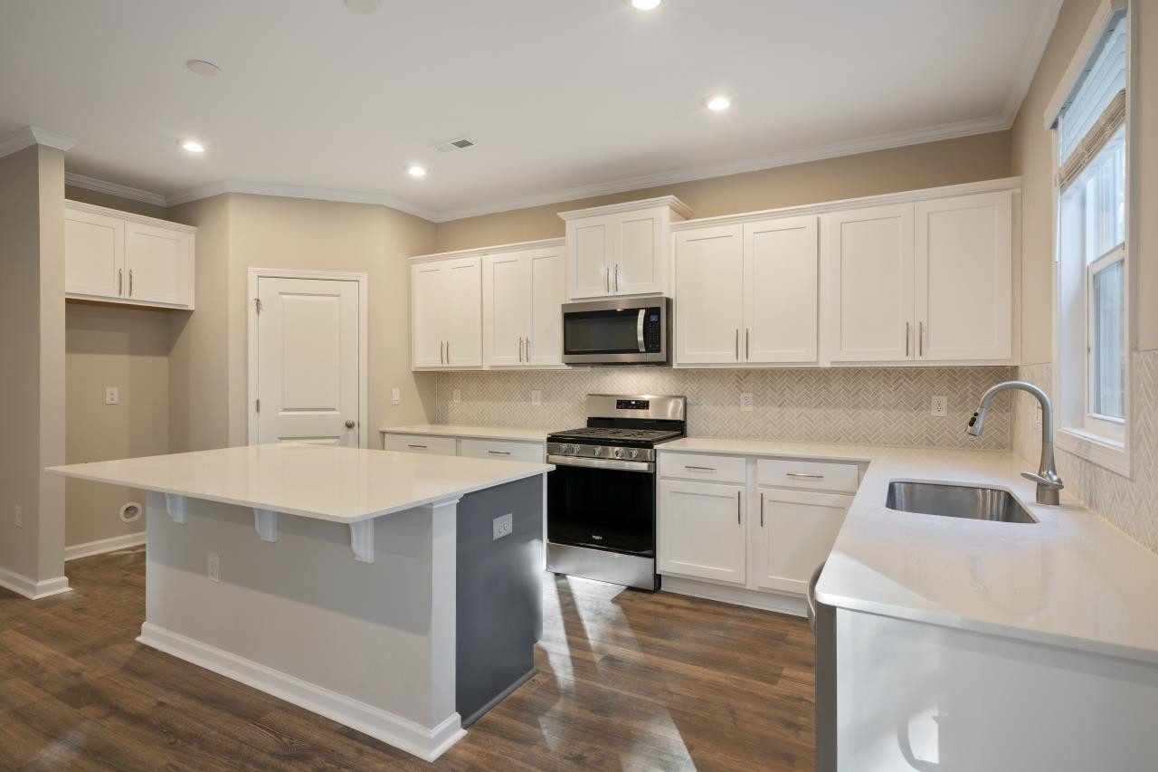 267 Madden Rose Loop Garner, NC 27529 - Photo 26 of 41 a kitchen with a sink dishwasher a stove top oven a refrigerator with white cabinets and wooden floor