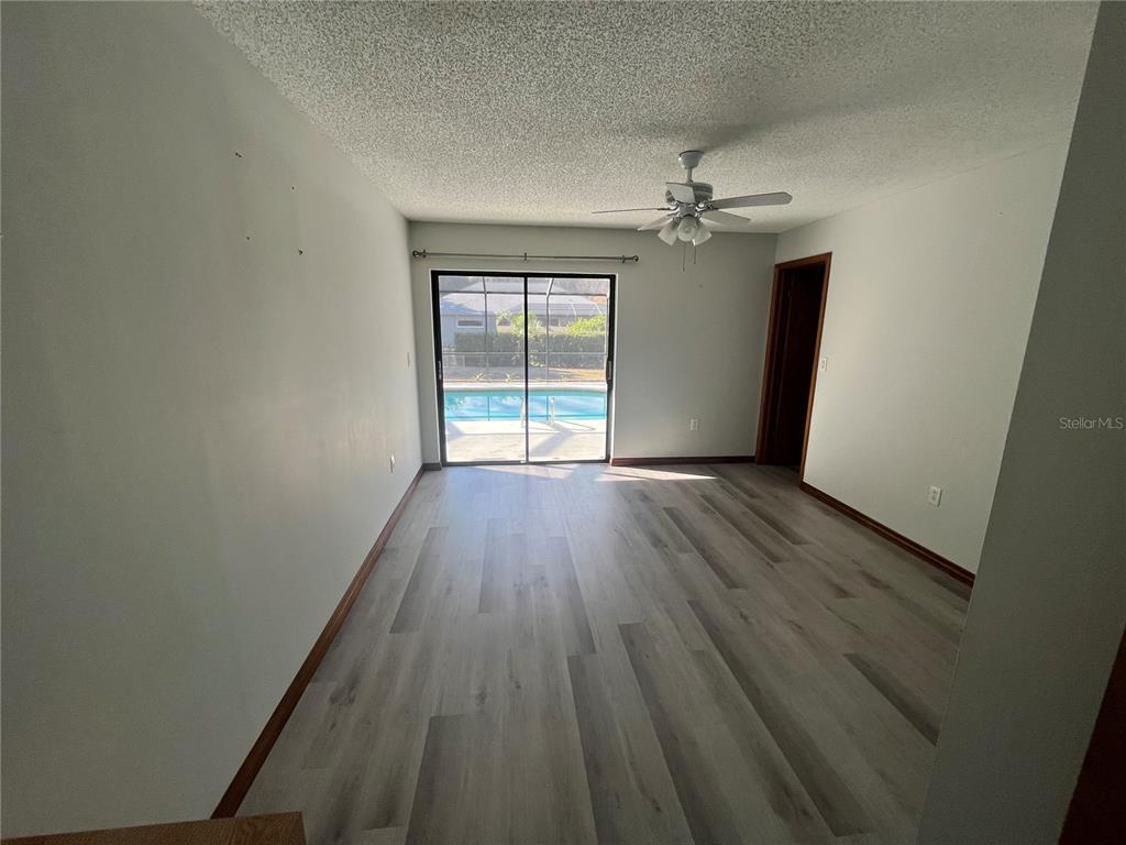 5375 Patricia Place Weeki Wachee, FL 34607 - Photo 48 of 61 an empty room with wooden floor ceiling fan and windows