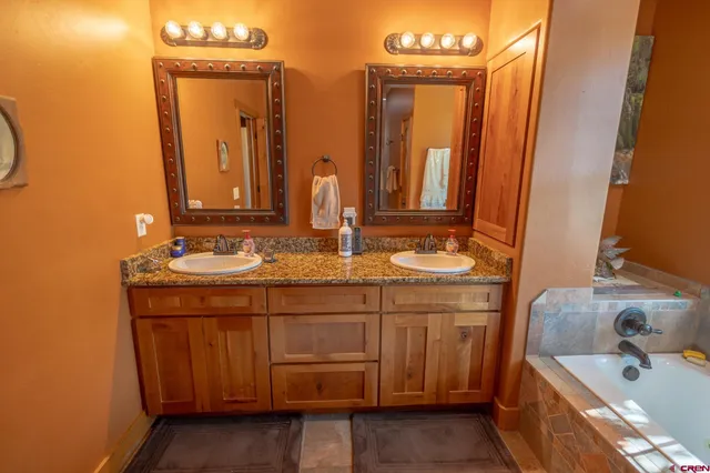 a bathroom with a double vanity sink a mirror and a bathtub