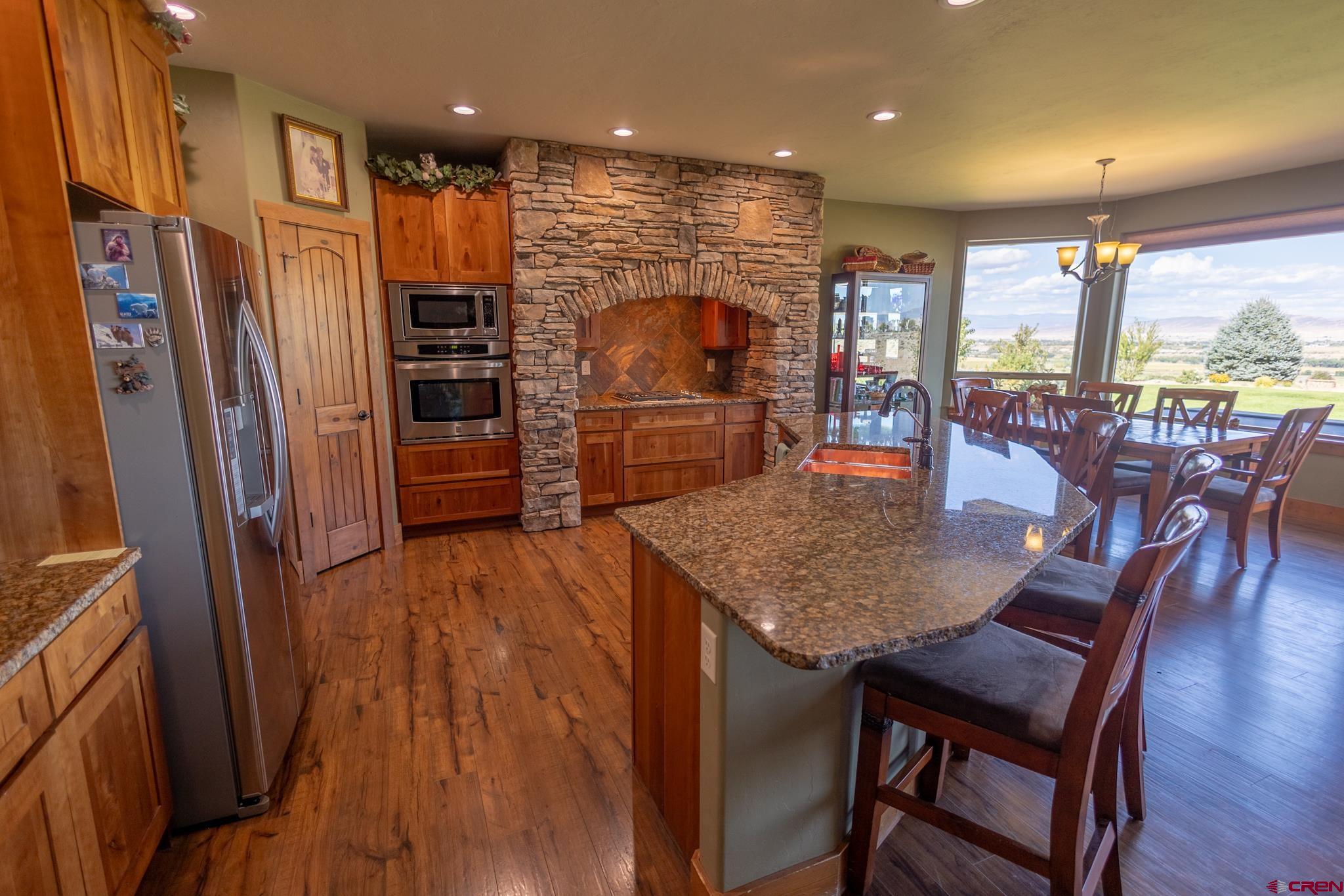 9550 High Mesa Road Olathe, CO 81425 - Photo 5 of 43 a kitchen with stainless steel appliances granite countertop a refrigerator a stove top oven a dining table and chairs