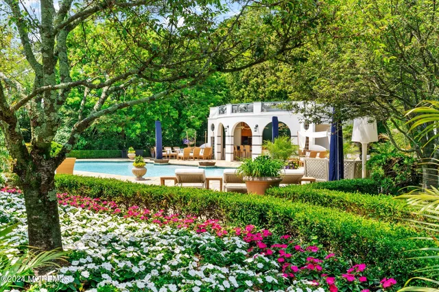 a view of a white house with a big yard and potted plants