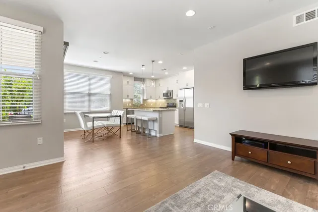 a living room with stainless steel appliances furniture and a flat screen tv