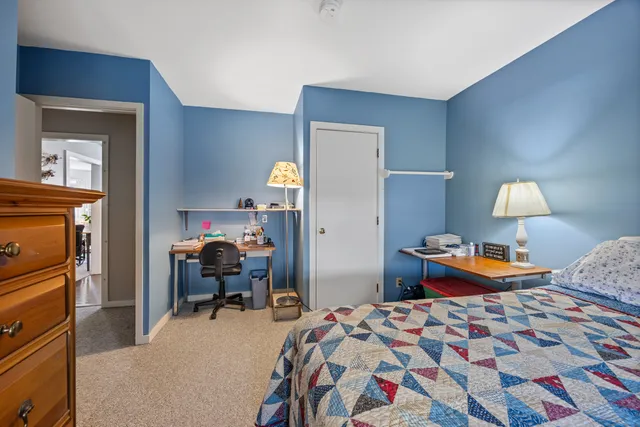 a bedroom with bed and a lamp on dresser