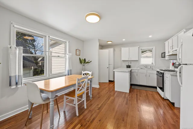 a kitchen with wooden floors and white stainless steel appliances