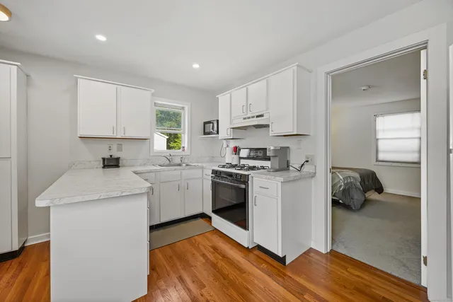 a kitchen with a sink dishwasher a stove and a refrigerator with wooden floor