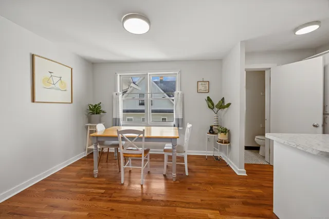 a dining room with wooden floor a chandelier a glass table and chairs