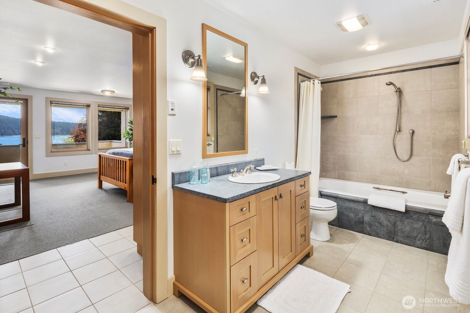 15283 Gibralter Road Anacortes, WA 98221 - Photo 32 of 40 a bathroom with a granite countertop sink a toilet a mirror and shower
