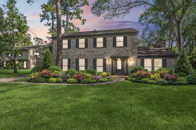 a view of a brick house with a big yard and large trees
