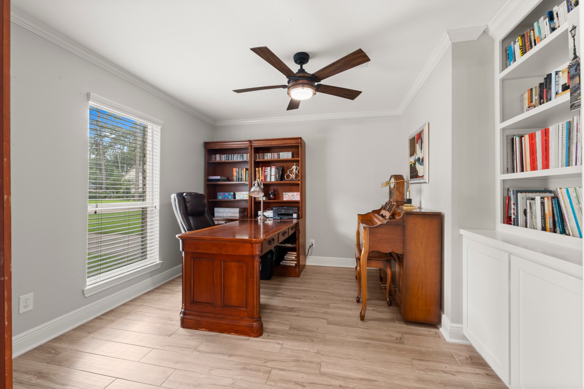 6030 Craigway Road Spring, TX 77389 - Photo 17 of 45 Home office featuring built-in bookshelves, and a large window. The room is well-lit with a ceiling fan offering a cozy and functional workspace.