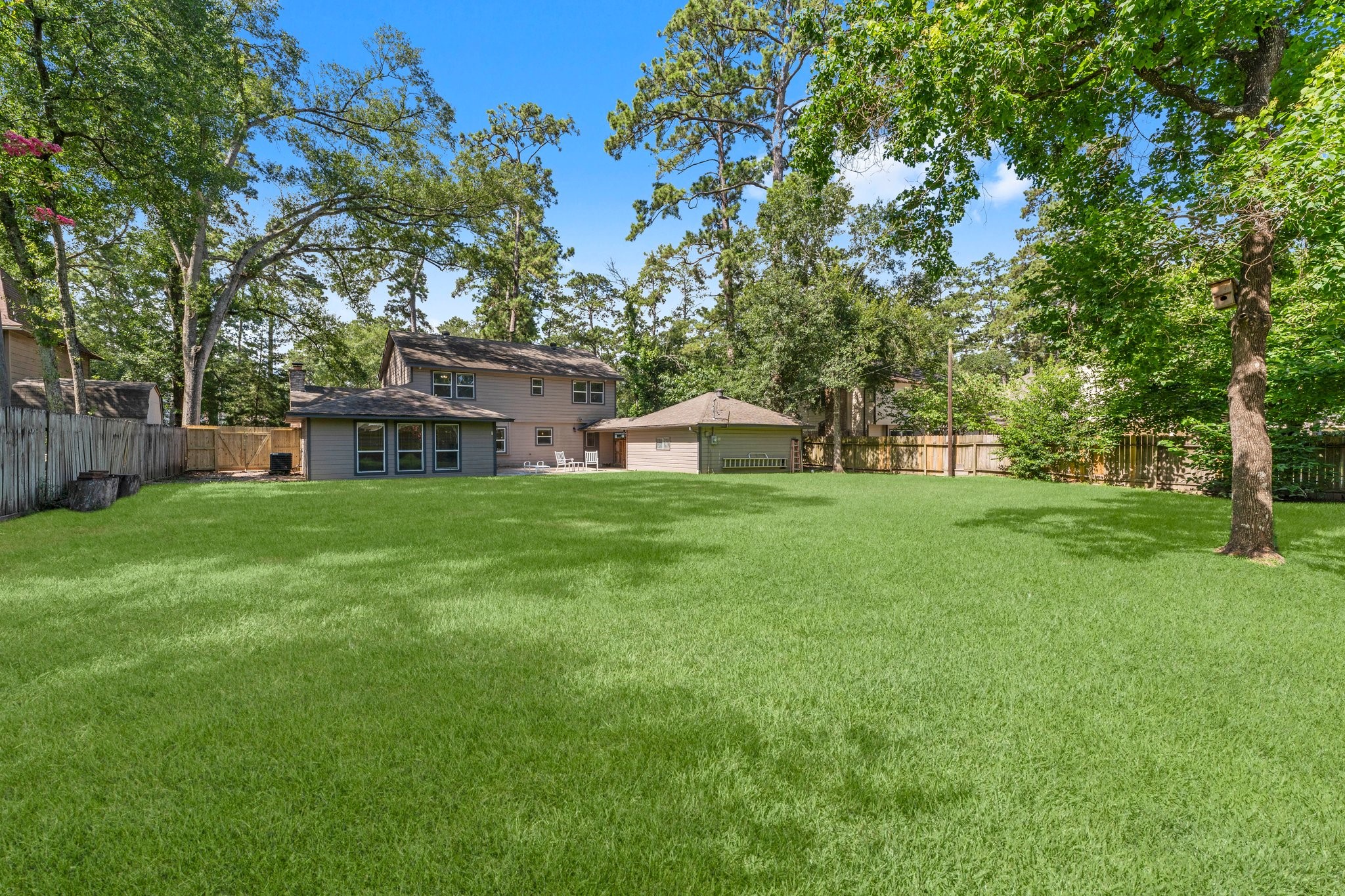 6030 Craigway Road Spring, TX 77389 - Photo 35 of 45 This photo shows a spacious backyard with a well-maintained lawn, surrounded by mature trees and a wooden fence for privacy.