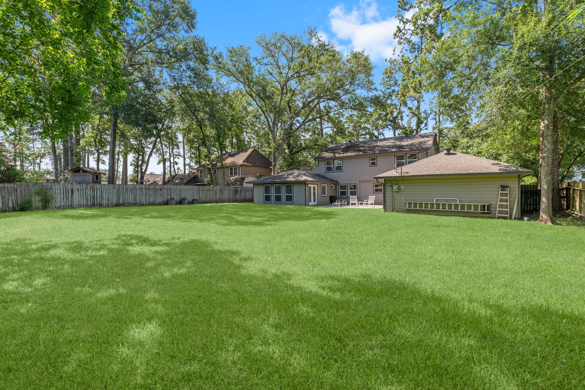 6030 Craigway Road Spring, TX 77389 - Photo 36 of 45 Spacious backyard with lush green lawn, mature trees, and a large two-story house featuring a patio.