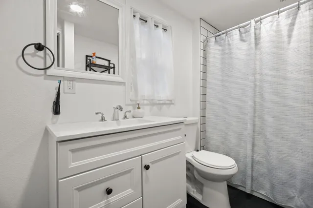 a bathroom with a granite countertop sink a toilet and a mirror