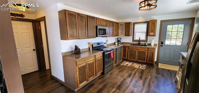 a kitchen with stainless steel appliances granite countertop a stove a sink dishwasher and a refrigerator with wooden floor