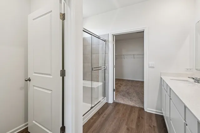 a walk in closet with wooden floor