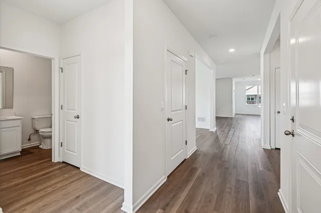 a view of a hallway with wooden floor and a bathroom