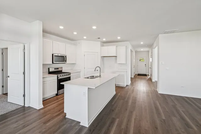 a large kitchen with a center island wooden floor stainless steel appliances and cabinets