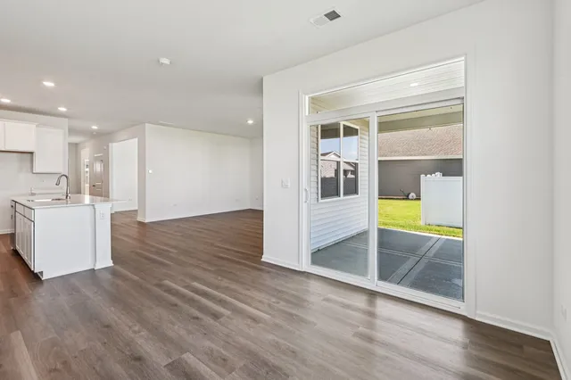 a view of a kitchen and an empty room with wooden floor