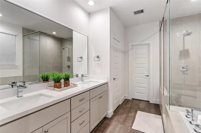 a spacious bathroom with a double vanity sink a large mirror a shower and a bathtub