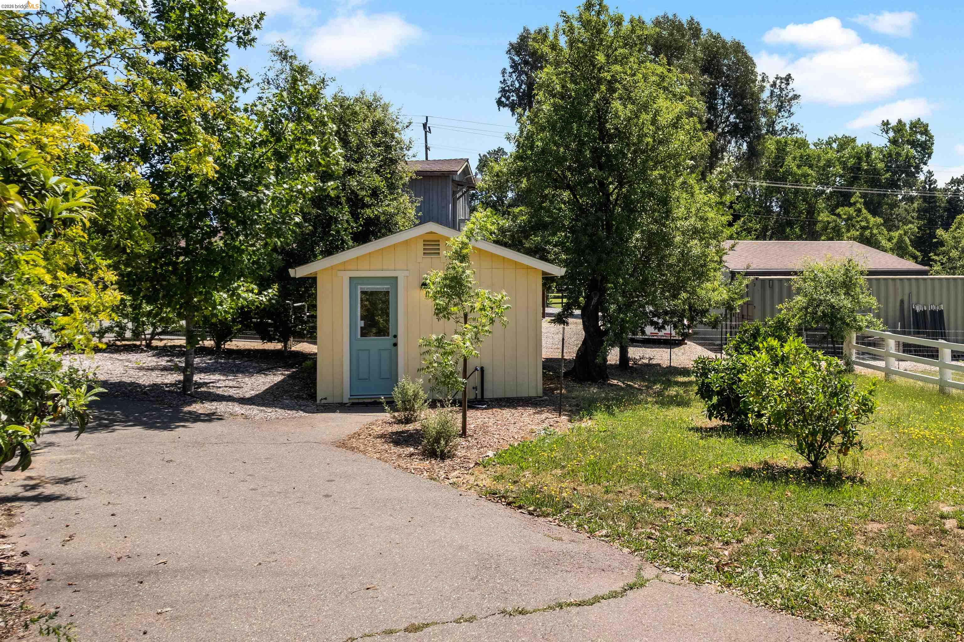 10474 Sheldon Road Elk Grove, CA 95624 - Photo 64 of 83 Detached yellow storage shed with a blue entry door
