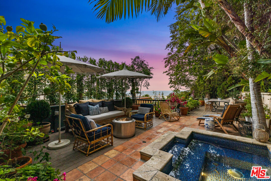 175 West Channel Road Santa Monica, CA 90402 - Photo 42 of 53 a view of a patio with couches table and chairs under an umbrella with a fire pit