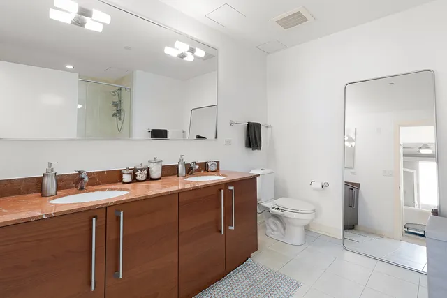 a bathroom with a toilet sink double vanity and mirror
