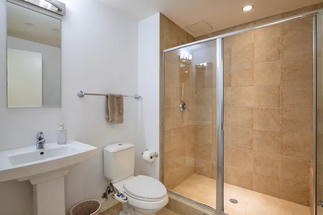 a bathroom with a shower sink vanity mirror and toilet
