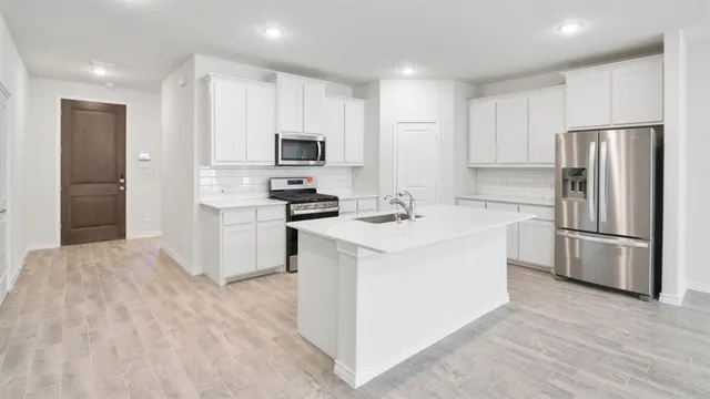 a kitchen with kitchen island a white cabinets and refrigerator