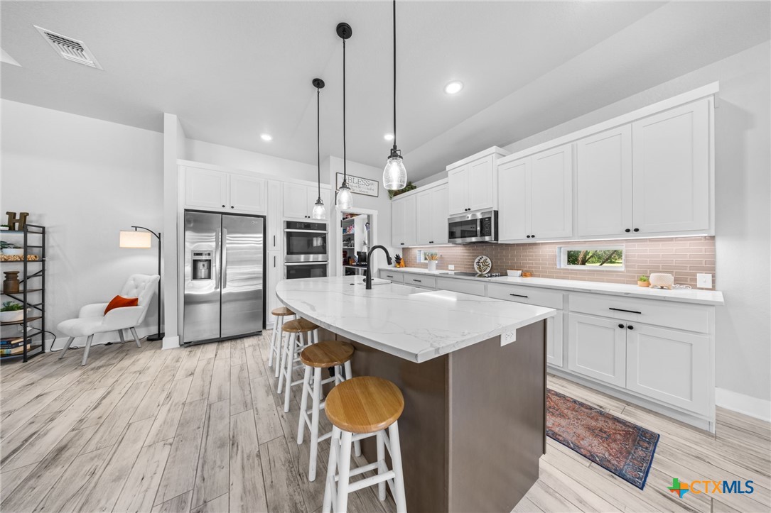 614 South Wheat Road Belton, TX 76513 - Photo 19 of 46 a kitchen with stainless steel appliances kitchen island granite countertop a sink a stove a refrigerator and white cabinets with wooden floor