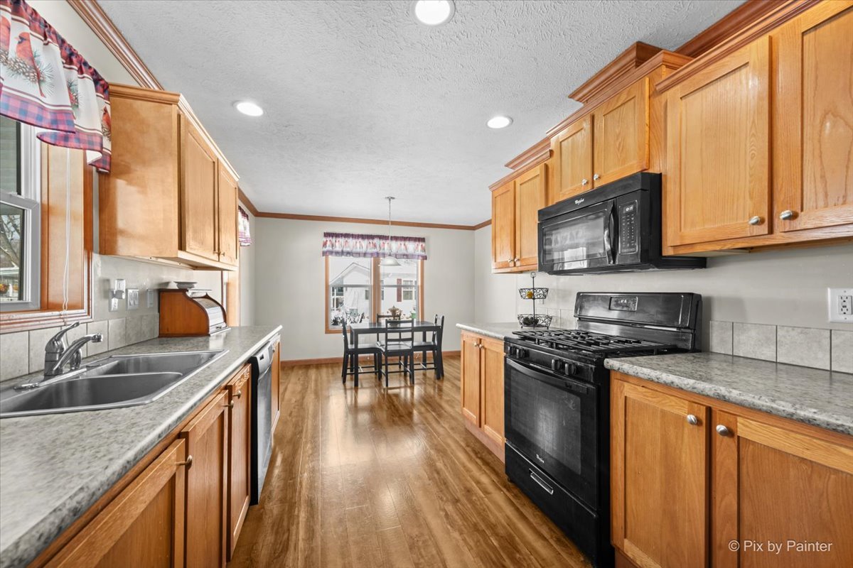 173 Northshore Road Elgin, IL 60123 - Photo 12 of 39 a kitchen with stainless steel appliances granite countertop a stove top oven a sink a dining table and chairs