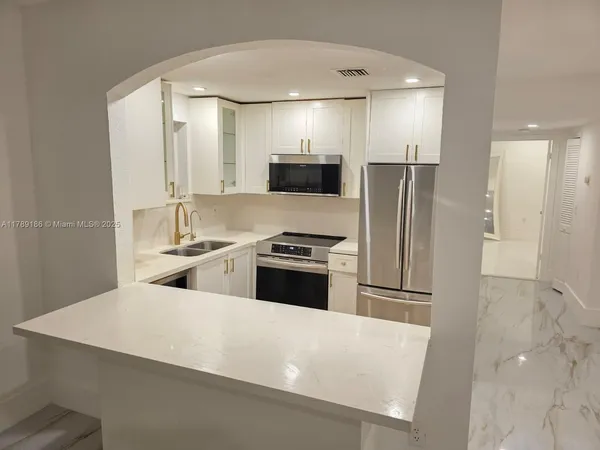 a large kitchen with a refrigerator a stove and a sink