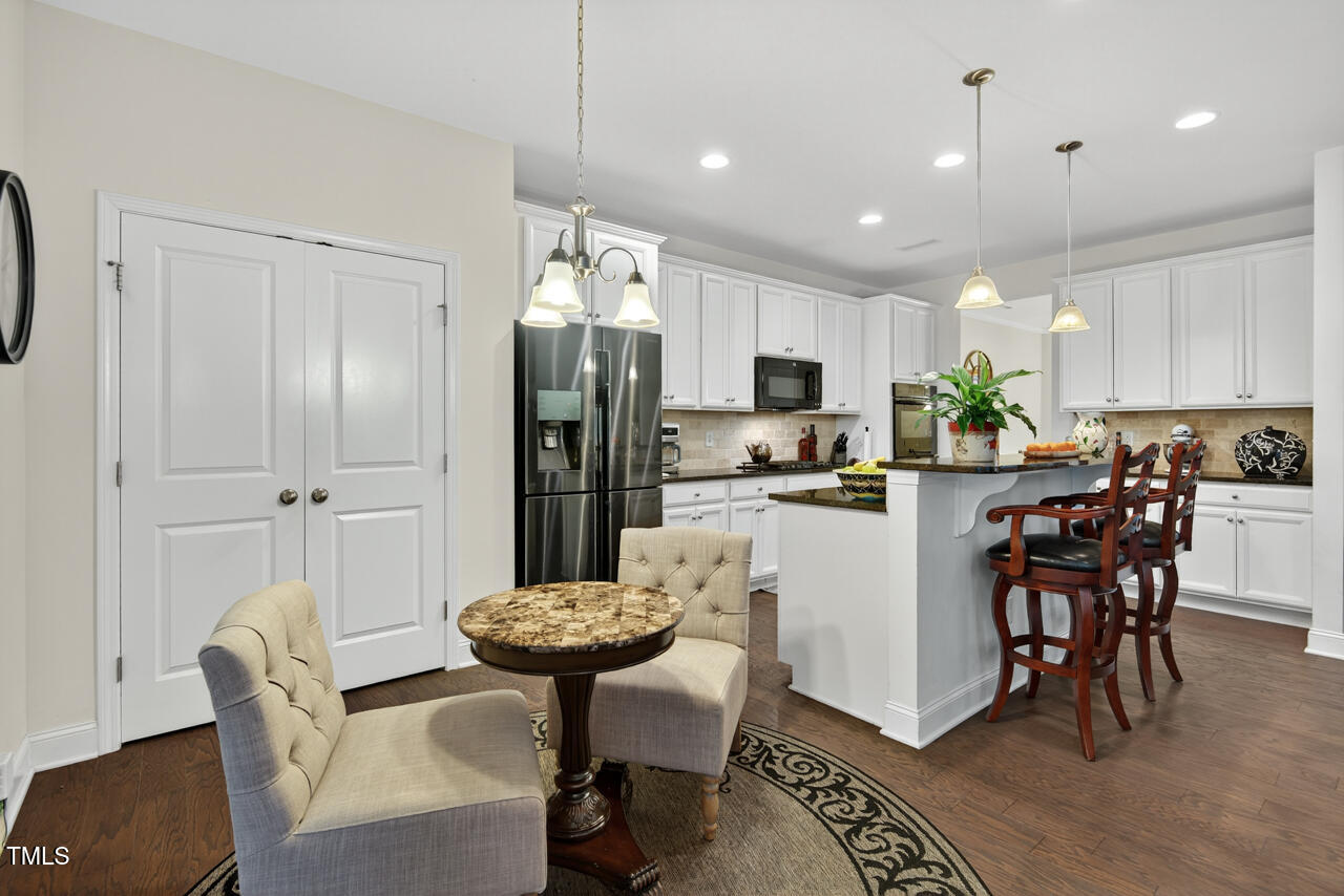 127 Willow View Lane Apex, NC 27539 - Photo 17 of 39 a kitchen with stainless steel appliances kitchen island granite countertop a refrigerator a stove a sink a dining table and chairs with wooden floor