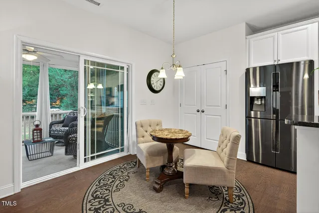 a kitchen with stainless steel appliances kitchen island granite countertop a refrigerator a stove a sink a dining table and chairs with wooden floor