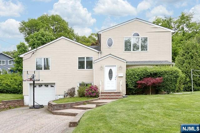 84 12th Street Cresskill, NJ 07626 - Photo 38 of 45 a view of a white house with a yard and table and chairs under an umbrella