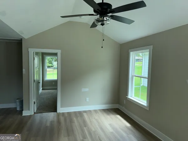 an empty room with windows and fan