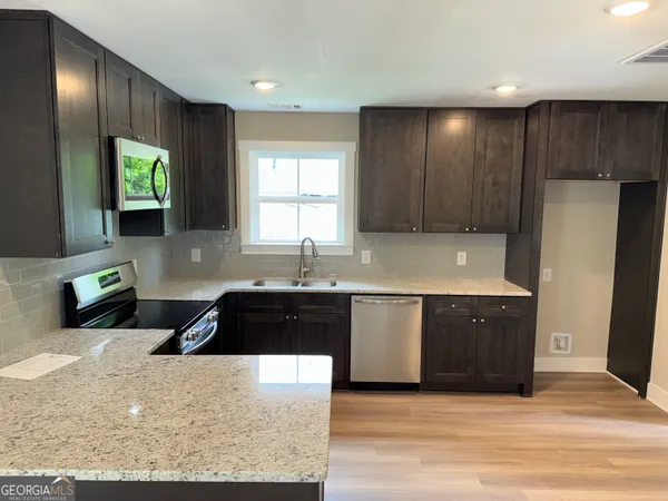 a kitchen with granite countertop wooden cabinets a stove a refrigerator and a sink