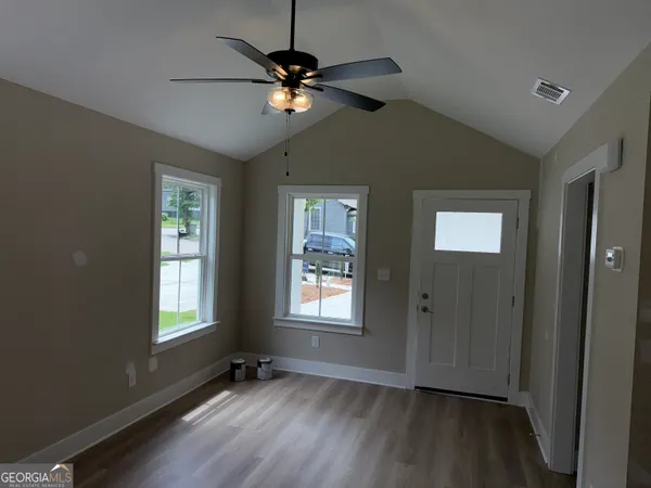 a view of an empty room with wooden floor and a window