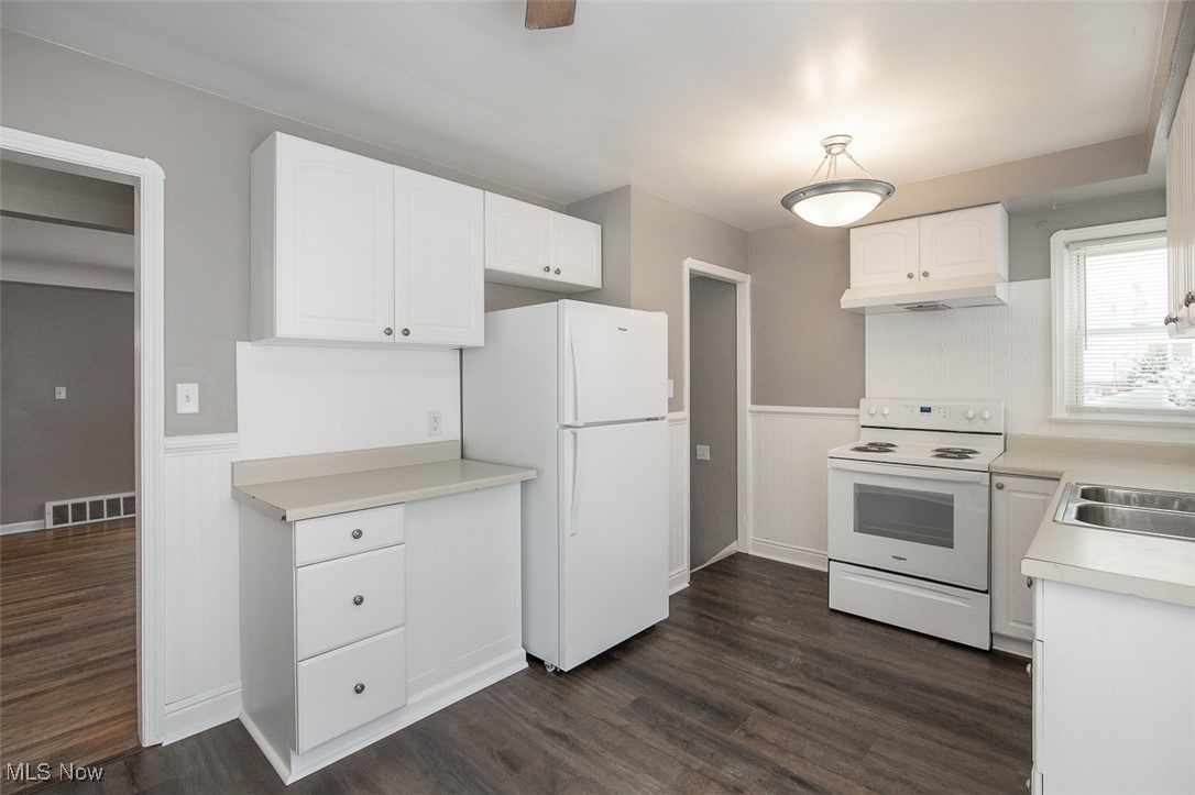 12328 Granger Road Cleveland, OH 44125 - Photo 21 of 37 Kitchen featuring a wainscoted wall, white appliances, light countertops, dark wood-style floors, and white cabinets