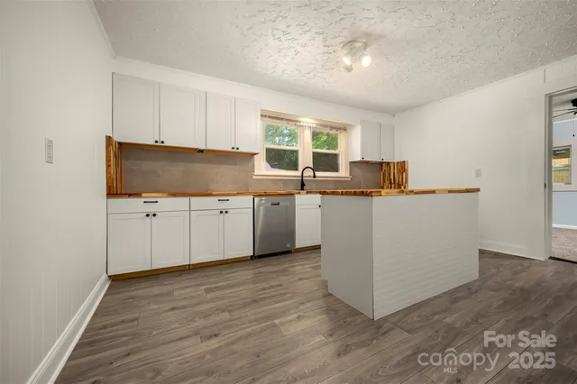 a kitchen with stainless steel appliances a sink a stove a refrigerator cabinets and a window