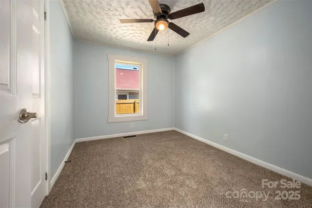 an empty room with windows and fan