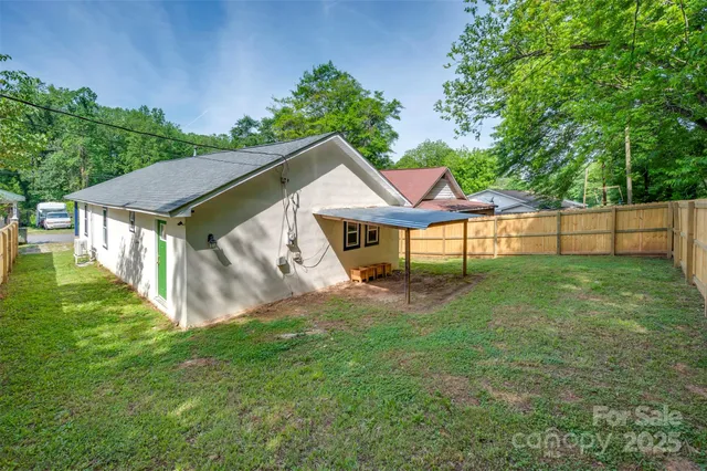 a view of a house with a yard plants and large tree