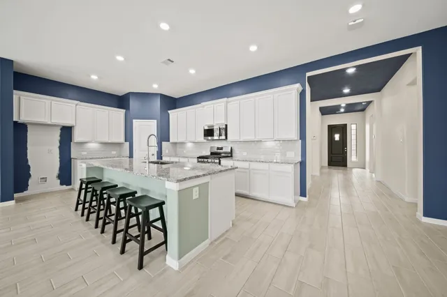a kitchen with stainless steel appliances granite countertop a kitchen island hardwood floor sink and stove