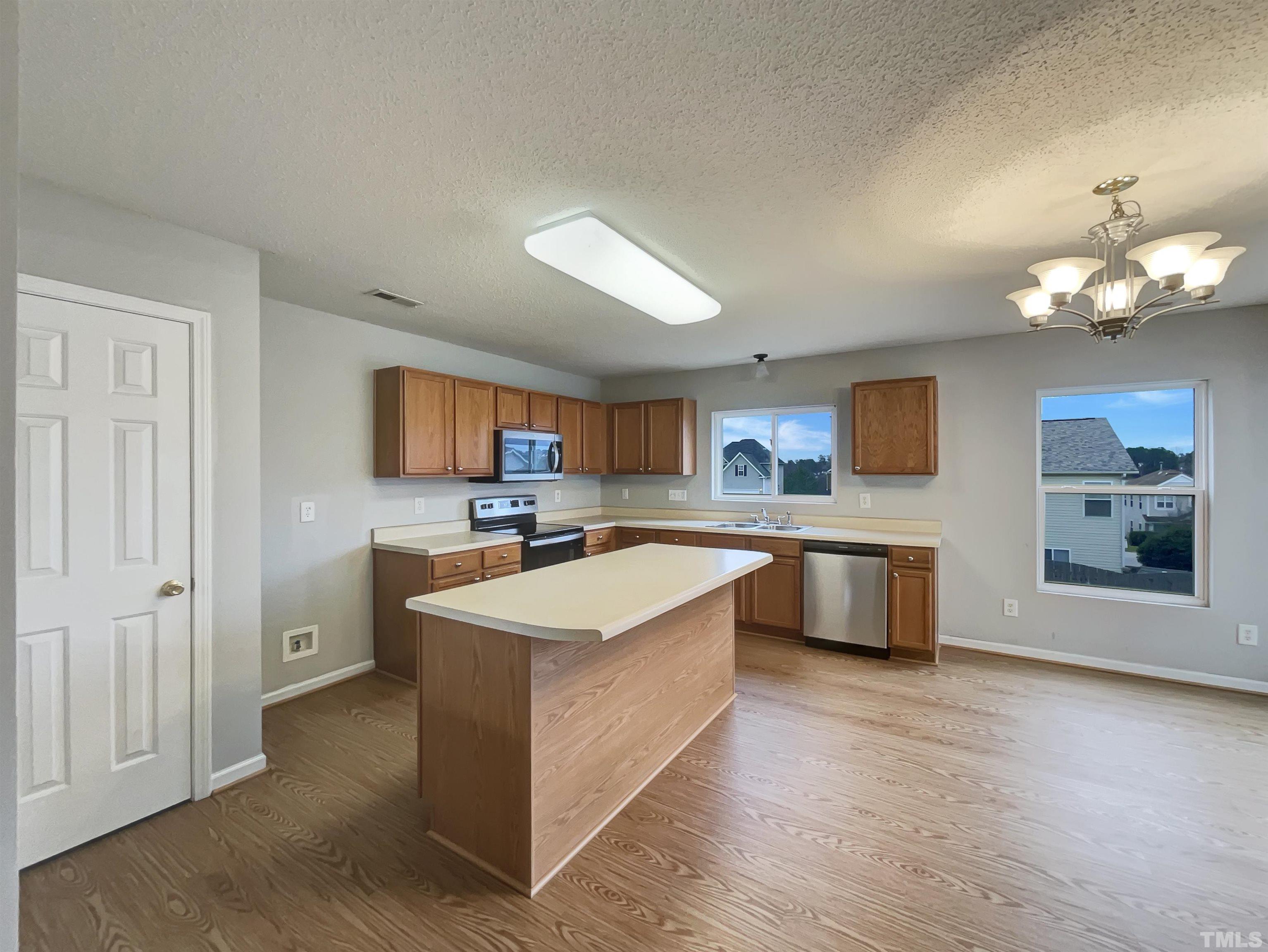 6036 Namozine Court Raleigh, NC 27610 - Photo 7 of 19 a large kitchen with kitchen island a sink a center island and stainless steel appliances