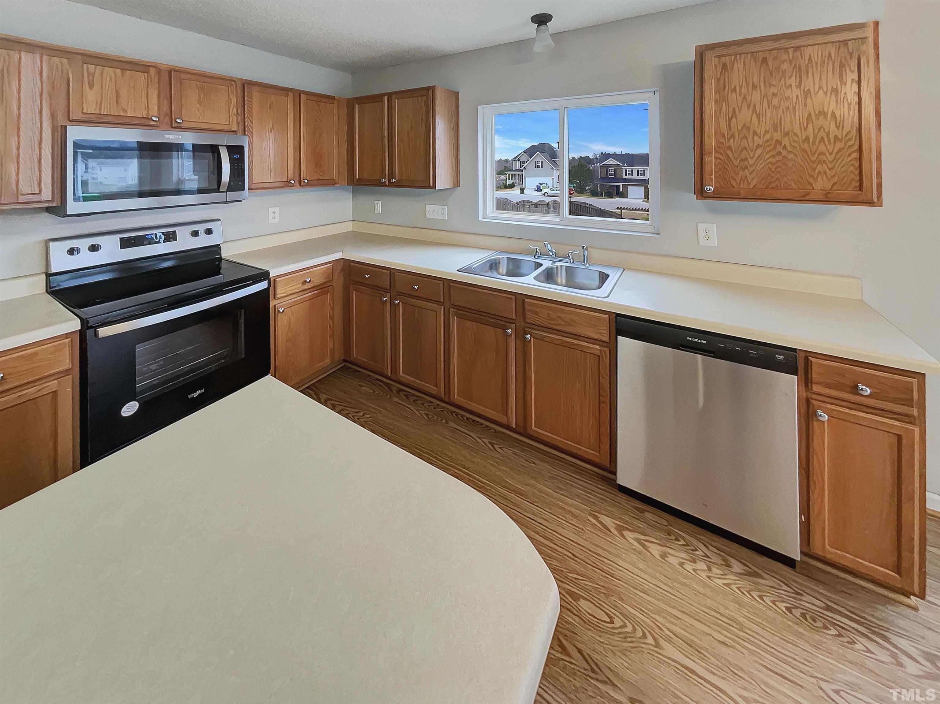 6036 Namozine Court Raleigh, NC 27610 - Photo 9 of 19 a kitchen with stainless steel appliances a stove microwave and sink